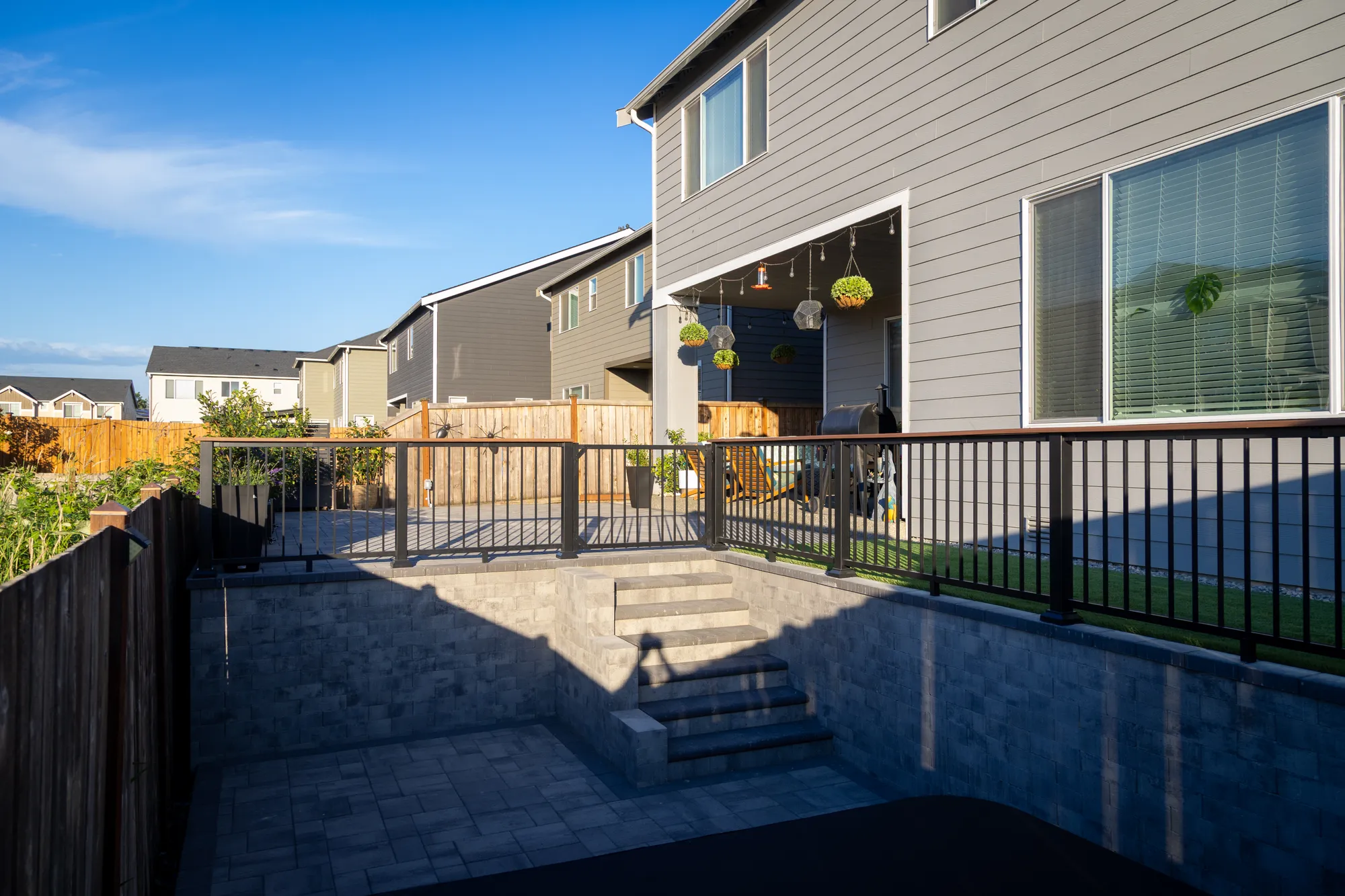 Two levels of segmental block retaining wall with connecting steps and aluminum railing in a Puyallup backyard
