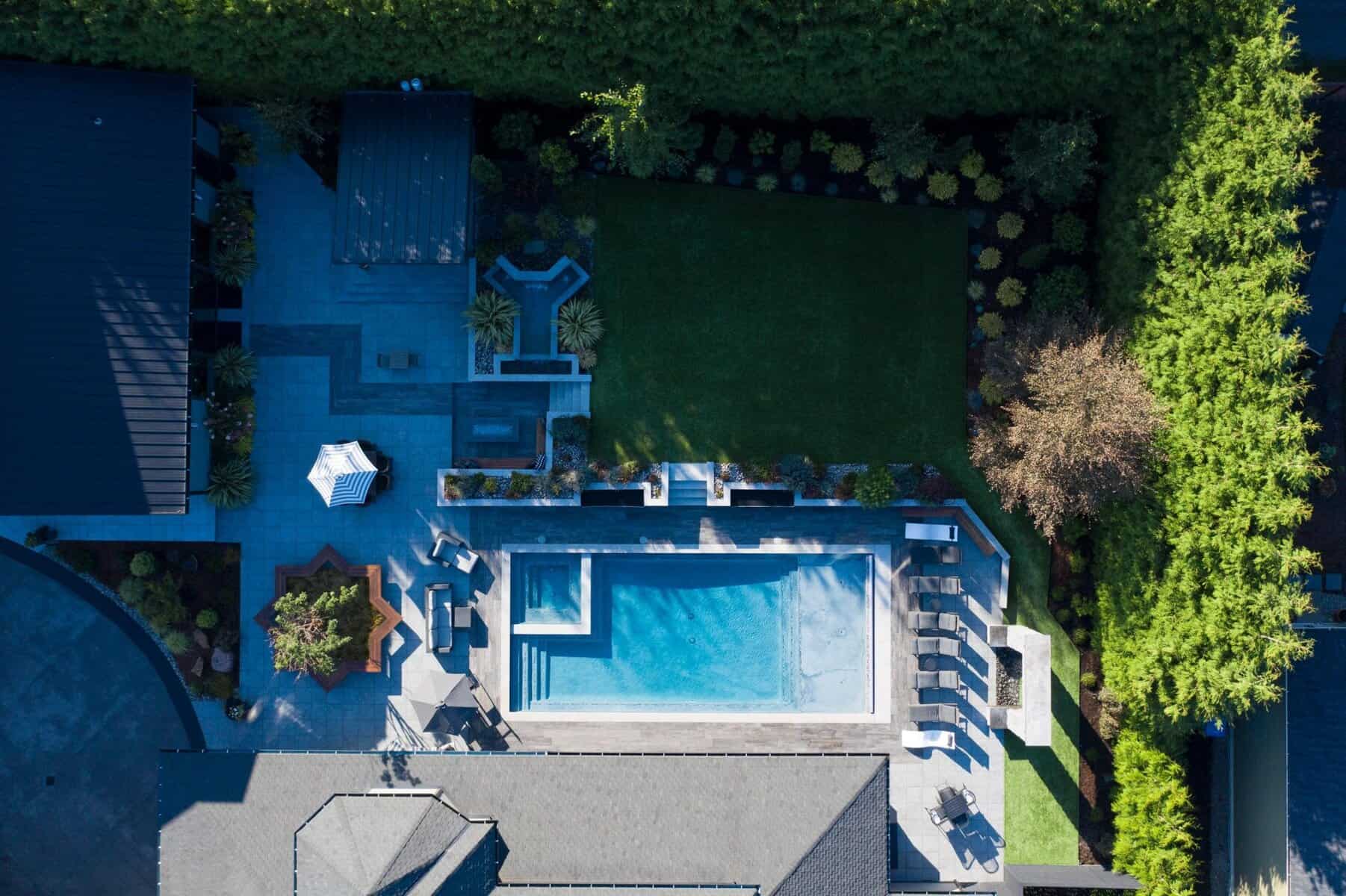 Drone view of porcelain paver pool surround with outdoor kitchen and water wall, East Tacoma