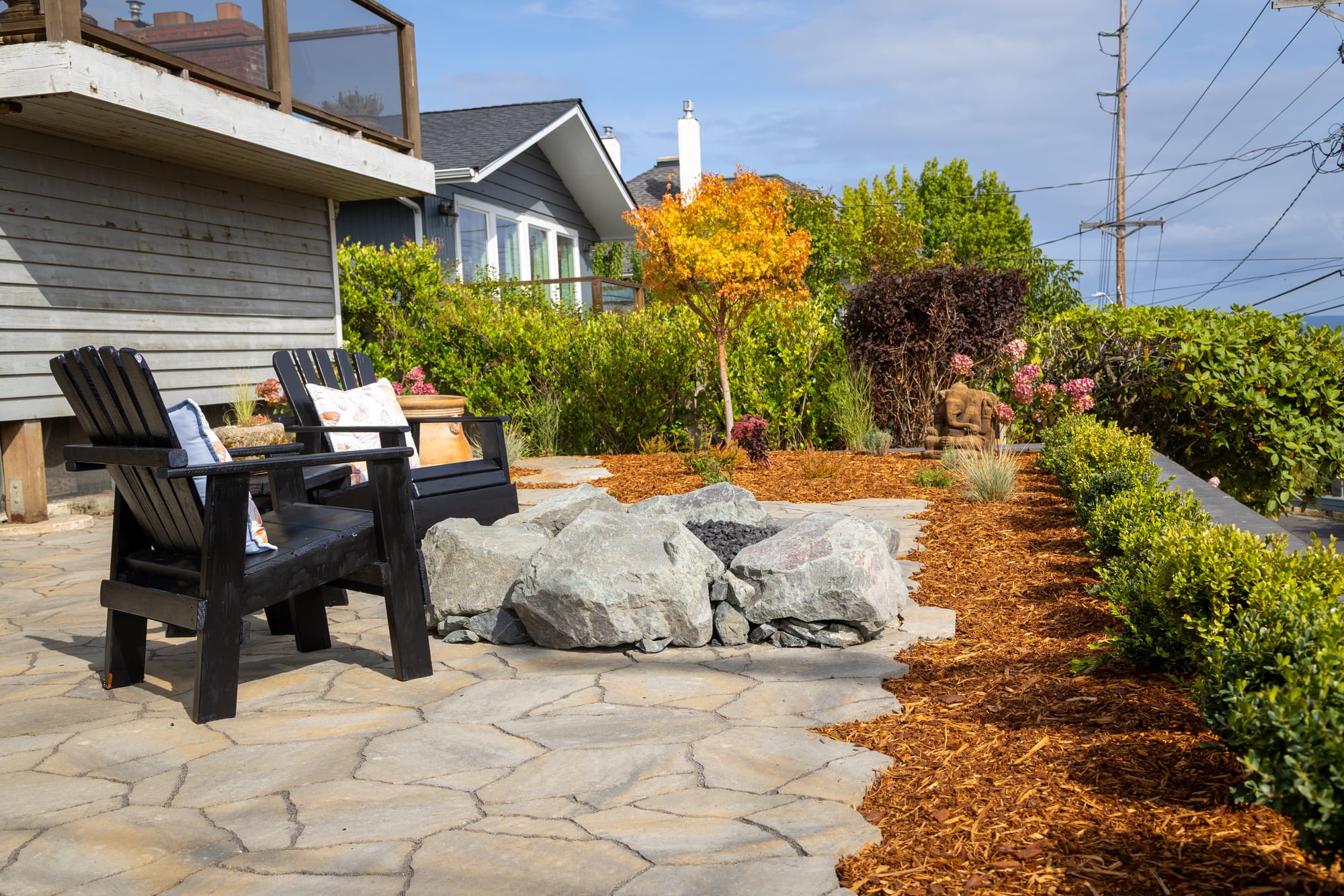 The fire pit and Adirondack chairs with a small maple in orange fall color behind